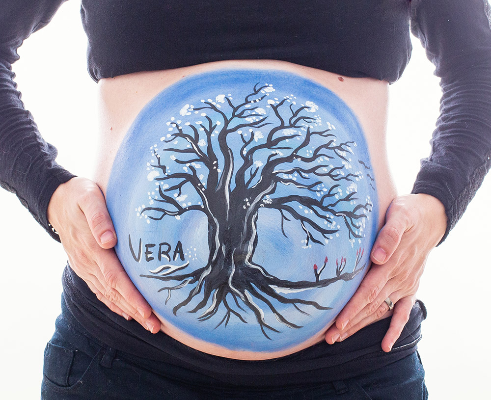 Foto de mujer embarazada con la tripa pintada con un arbo de la vida en una sesion de belly painting