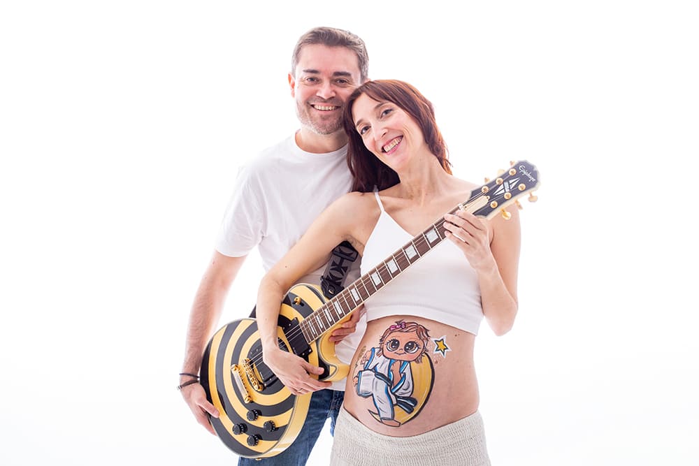 foto de pareja en una sesion de belly painting en estudio con una guitarra