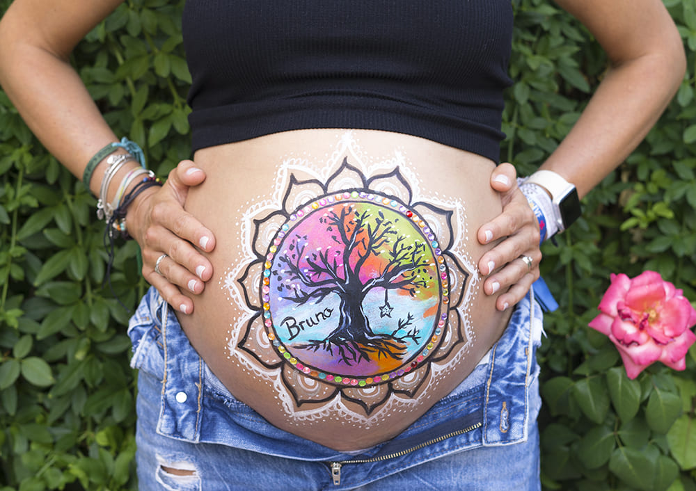 foto de tripita pintada de una mujer embarazada en su baby shower en leganes con un dibujo del arbol de la vida con muchos colores